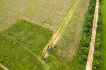 Aerial view of an agricultural field and harvester harvesting in autumn day