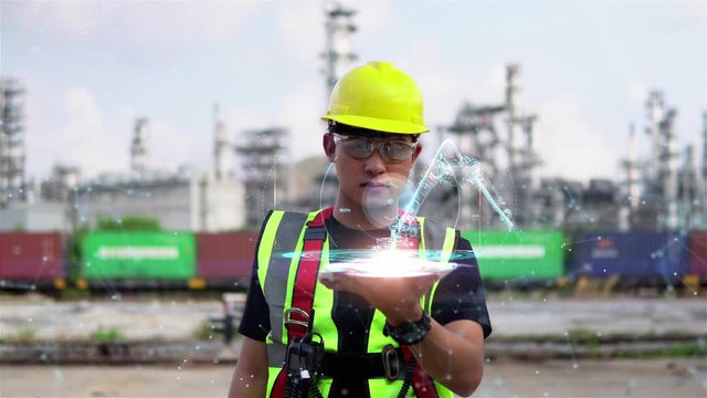 Male Industrial Engineer Works with glasses shows a conceptual hologram Industrial robot arm consisting on blurred background of large industry 