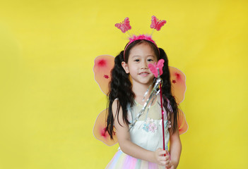 asian little child girl dressed in fairy costume isolated on yellow