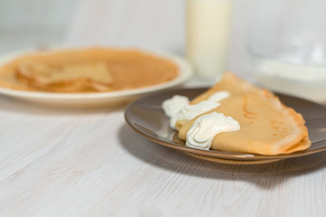 Maslenitsa is a holiday at the end of February . pancakes with sour cream and milk on a light wooden background. close up. blini. space for text.