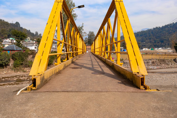 Yellow steel bridge over river in himachal pradesh in Kangra village, india