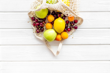 Textile eco bag with fruits on white wooden background top-down copy space
