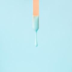 liquid mint wax or sugar paste for depilation drains from the stick on mint background. The concept...