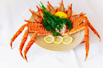 Red king crab and shrimp on a plate with lemon and dill. White background