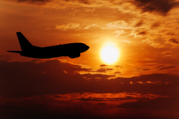 Fototapeta na wymiar Airplane In The Sky At Sunset. Travel background with passenger plane.