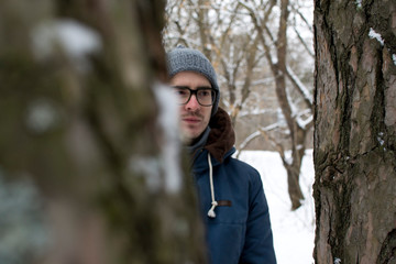 A young man is hiding behind a tree