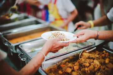 The hands of the poor apply for food from rich people who donate food.