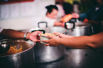 The hands of the poor apply for food from rich people who donate food.