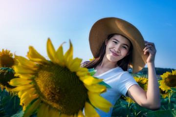 Beautiful woman in a beautiful blooming sunflower field. Happy woman summer sunset day