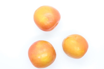 Ripe orange plums perched on a white background