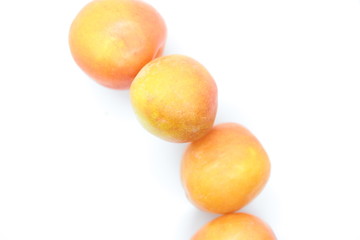Ripe orange plums perched on a white background