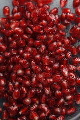Pomegranate seeds with water drops. Texture for the background. Ripe berries of pomegranate. Red texture of the granules in the macro.