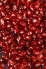 Pomegranate seeds with water drops. Texture for the background. Ripe berries of pomegranate. Red texture of the granules in the macro.