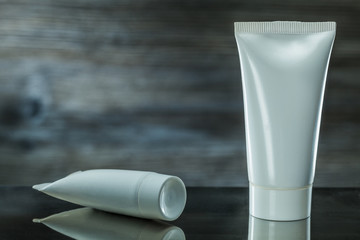 two white tubes skincare items on dark background