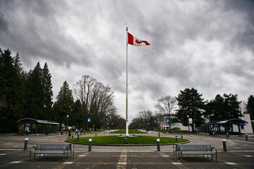 Canadian Flag Flying in the wind on a Cloudy day in a University Campus 
