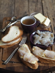 Breakfast, lunch, snack. Sandwiches with butter and freshly salted fish pike on a cutting kitchen board. XE fish salad. Wooden background.