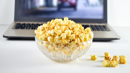 laptop and popcorn in a bowl on the table, home movie show