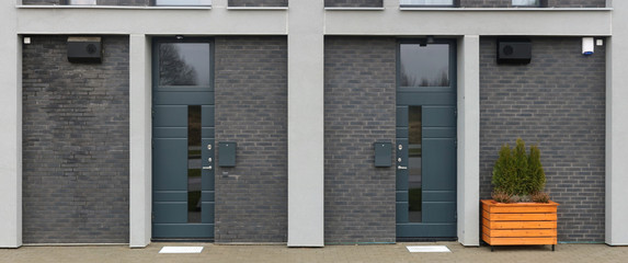 Front  wall of a mass production standard low cost  unfinished residential building with armed doors and  windows