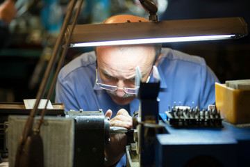 Belarus, the city of Gomil, April 24, 2019. Jewelry industry. Worker engraves diamonds.