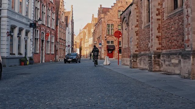 Belgium, Bruges - April 2019: man going to job on bike in the center of city