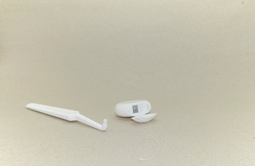 White toothbrush  for the care of braces and dental implants and dental floss on light beige pastel background. 
