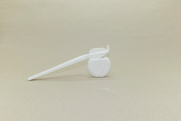 White toothbrush  for the care of braces and dental implants and dental floss on light beige pastel...