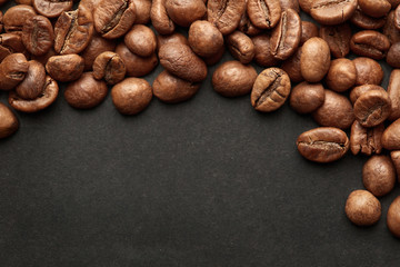 Naklejka premium Brown roasted coffee beans on dark background. Espresso dark, aroma, black caffeine drink. Closeup isolated energy mocha, cappuccino ingredient.
