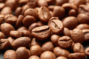 Brown roasted coffee beans on dark background. Espresso dark, aroma, black caffeine drink. Closeup isolated energy mocha, cappuccino ingredient.