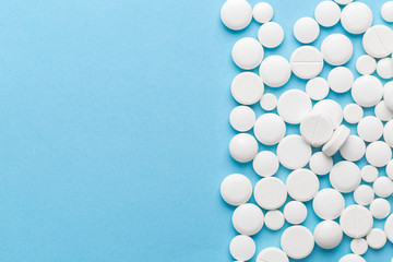 scattered white pills on a blue table. Layout for special offers such as advertising or other ideas. The concept of medicine, pharmacy and healthcare. Space for copy. flat lay for text or logo.