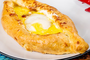 Caucasian dish khachapuri with egg served on a white plate
