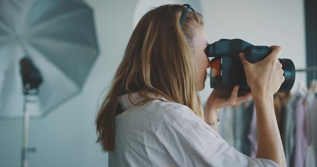 Young professional female photographer taking photos in a photo studio, creative industry jobs concept