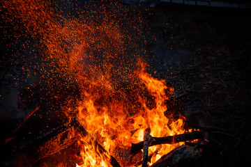 Campfire flame with sparks flying up at night