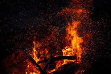 Campfire flame with sparks flying up at night