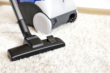Canister modern vacuum cleaner blue for cleaning the house on the background of a soft beige...