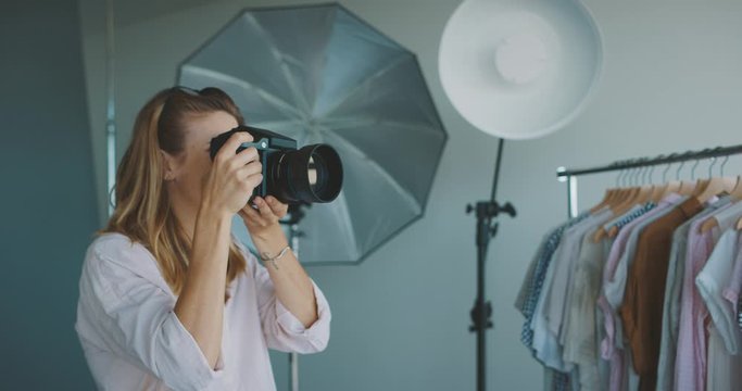 Young professional female photographer taking photos in a photo studio, creative industry jobs concept
