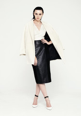 Full length fashion shot of beautiful model in white coat and black skirt. Isolated on white background - 321422092