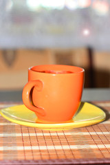 orange coffee cup and yellow saucer on a wooden table