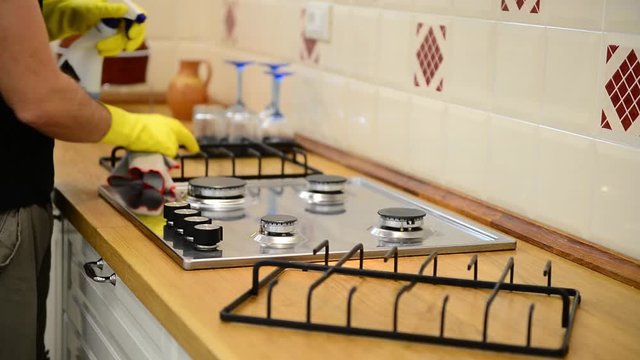 Caucasian man cleaning cookers with spray, spoonge and gloves