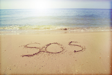 SOS inscription in the sand on the seashore