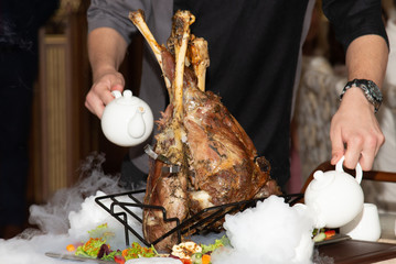 Chief cooking rack of lamb. Meat, sauceboats, smoke