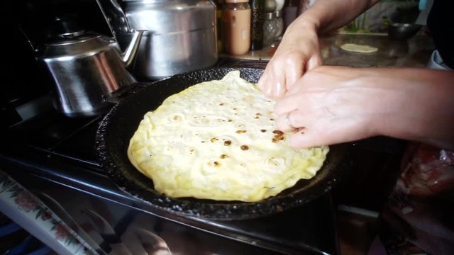 The most traditional Moroccan dishes. A Moroccan women cooking bread on a cast iron pan. making Rrissa. Moroccan kitchen