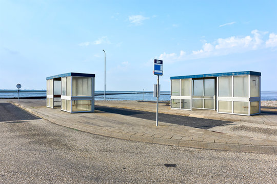 Two bus stops without people in an empty desolate landscape near the sea under a blue sky. Image with copy space.
