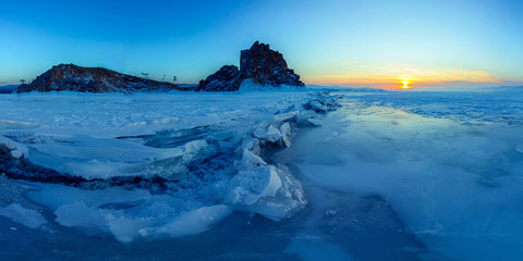 Big cracks in the ice of Lake Baikal at the Shaman Rock on Olkhon Island.. Wide panorama