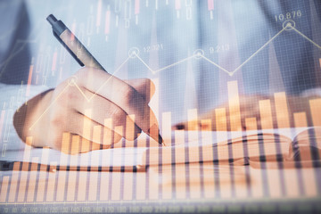 Multi exposure of woman's hands making notes with forex graph hologram. Concept stock market...