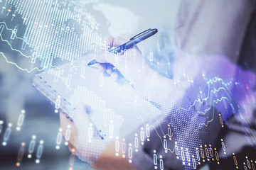 Multi exposure of hands making notes with forex chart huds. Stock market concept.