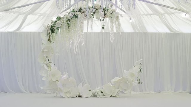 Beautiful cozy large wreath for the wedding, under which the bride and groom become, and the wedding ceremony takes place. Large spacious white wedding room with white chairs for guests. Wedding party