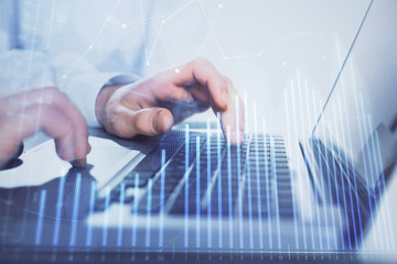 Double exposure of market chart with man working on computer on background. Concept of financial analysis.