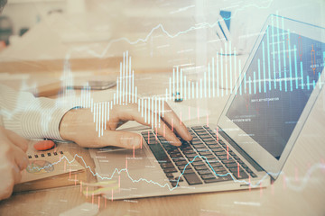 Double exposure of stock market graph with man working on laptop on background. Concept of...