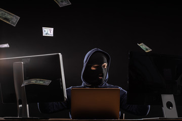 young hacker man in balaclava successfully finished hacking , sit in the hood of pullover,...