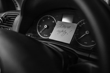 Writing drive safely on memo post reminder. Text on sticky paper inside car dashboard.